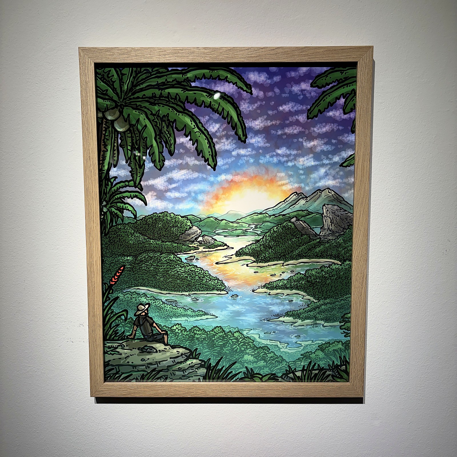 A pale oak frame on a white gallery wall: a tropical river at sunset.